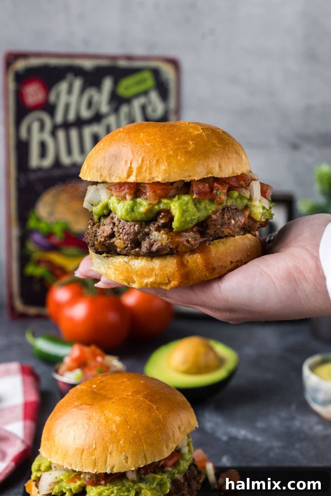 Fiesta Burger 3 A hand holding up a deliciously prepared Taco Burger, highlighting its stacked layers of seasoned patty and fresh toppings, ready to be enjoyed.