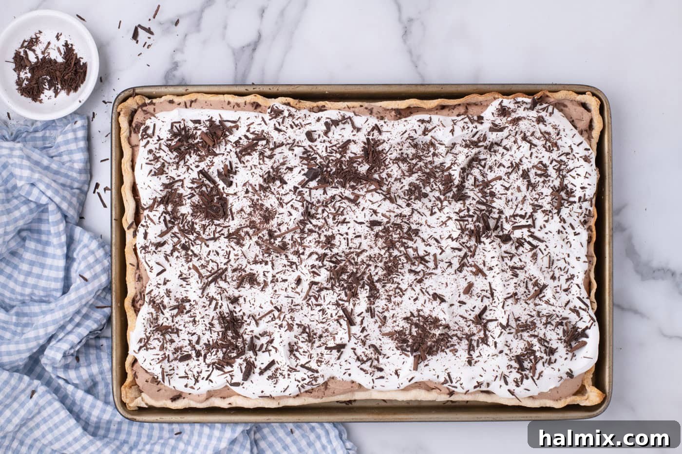 An overhead view of a completed French Silk Slab Pie, topped with whipped cream and adorned with delicate chocolate shavings, ready to be served.