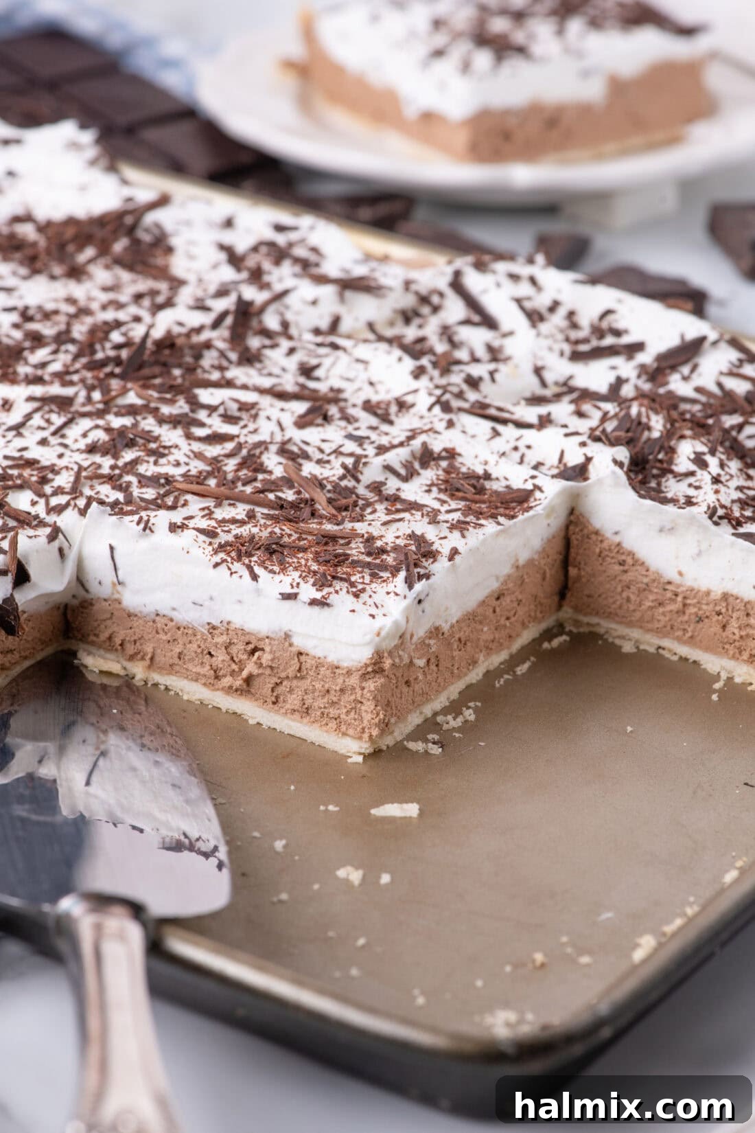 Close-up photo of a French Silk Slab Pie with several slices already removed, highlighting its rich chocolate interior and fluffy topping.