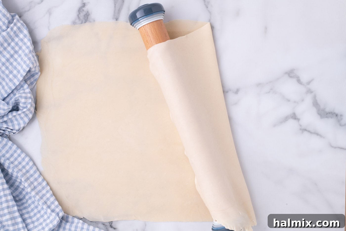 Pie crust being draped over a rolling pin for easy transfer to the baking pan.