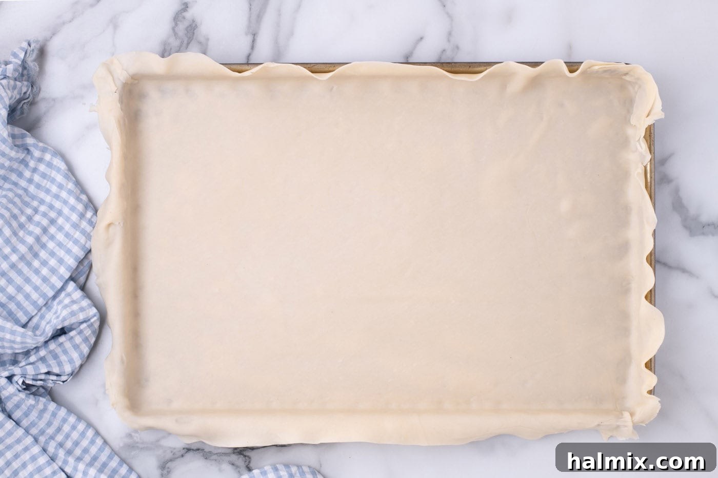 Pie crust successfully placed and fitted into a jelly roll pan, ready for further preparation.