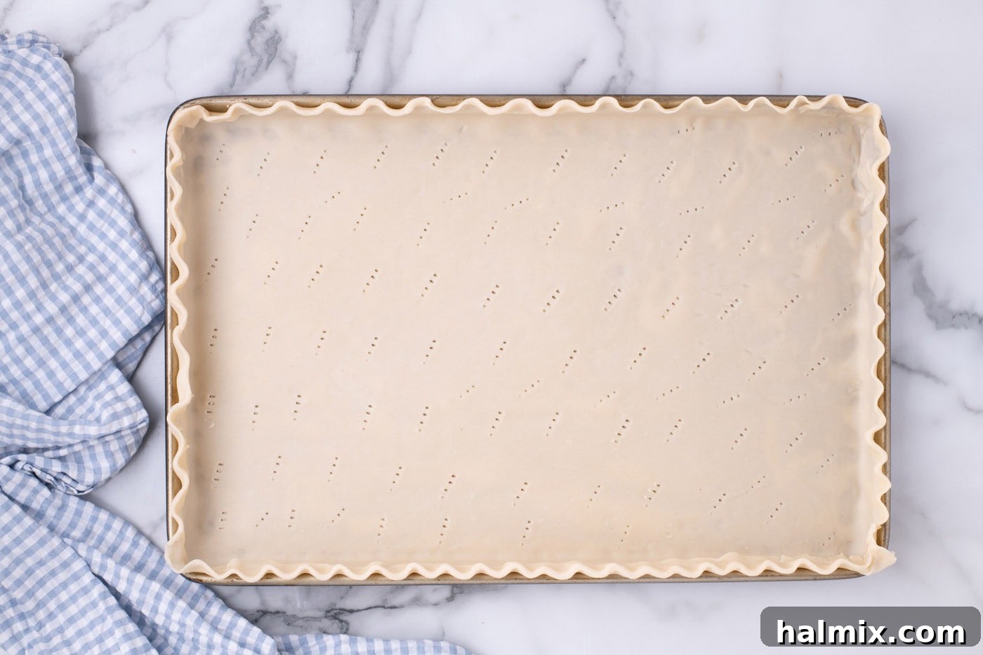 Pie crust in a jelly roll pan with neatly fluted edges, prepared for baking.