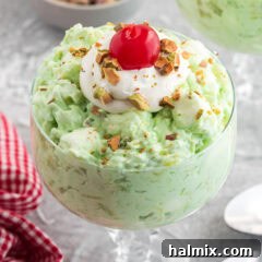 Emerald Cloud Dessert 11 Close up photo of Watergate Salad in a bowl topped with cool whip and a cherry