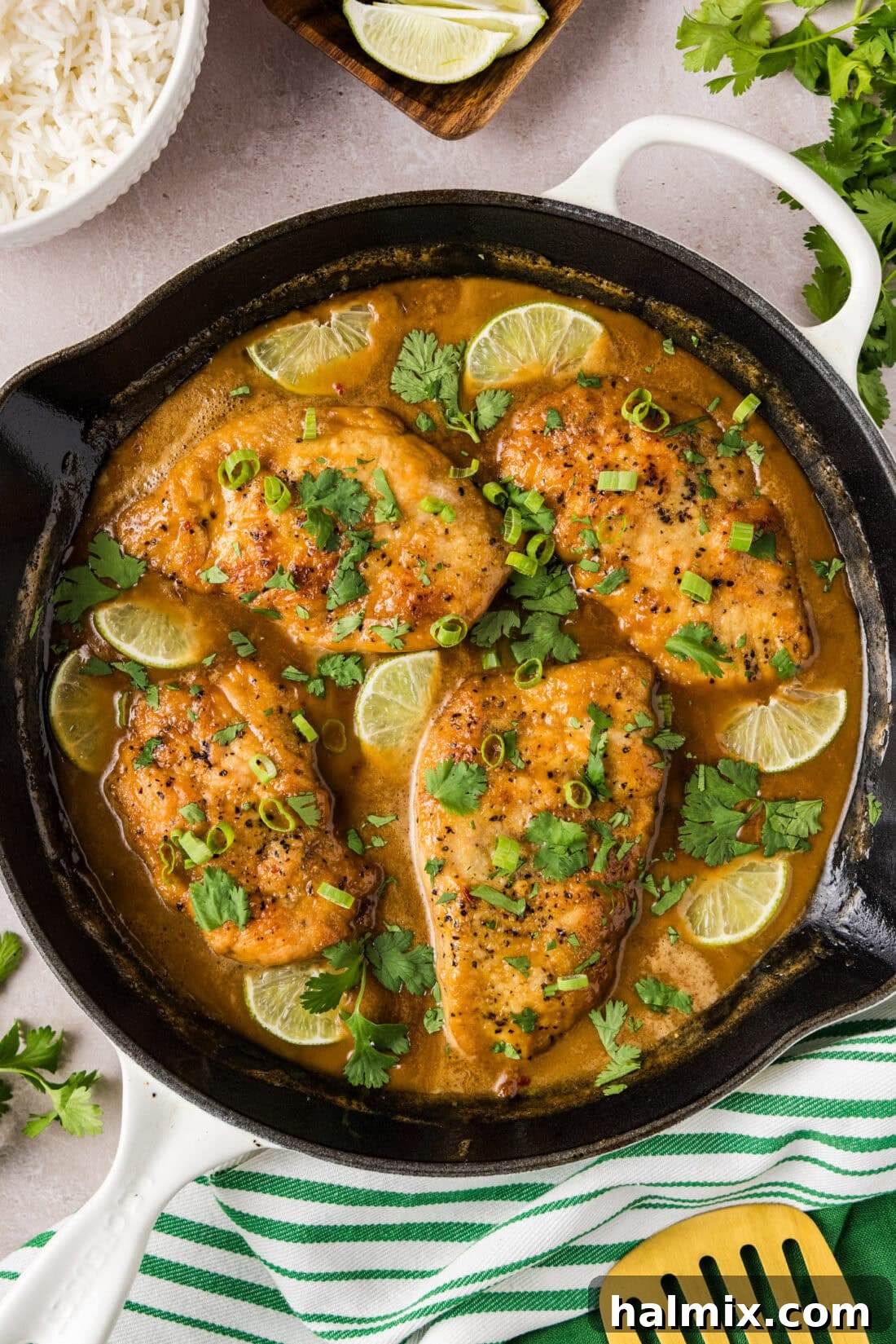 Tropical Coconut Chicken 2 Golden-brown skillet of Coconut Chicken garnished with fresh lime wedges and sliced green onions.