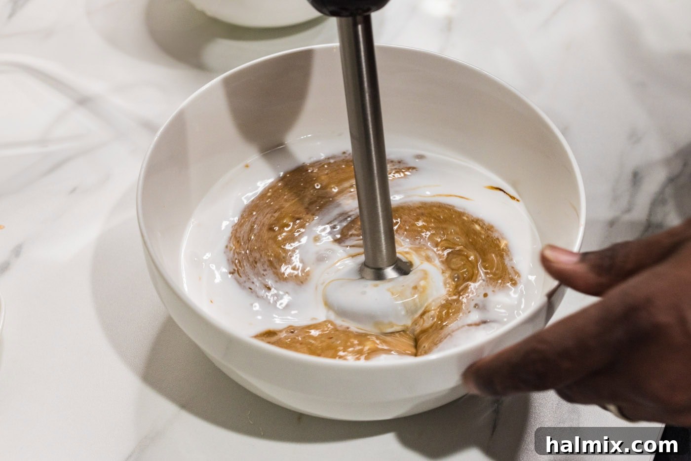 Tropical Coconut Chicken 7 An immersion blender mixing coconut milk, honey, sweet chili sauce, soy sauce, garlic, and ginger in a bowl.