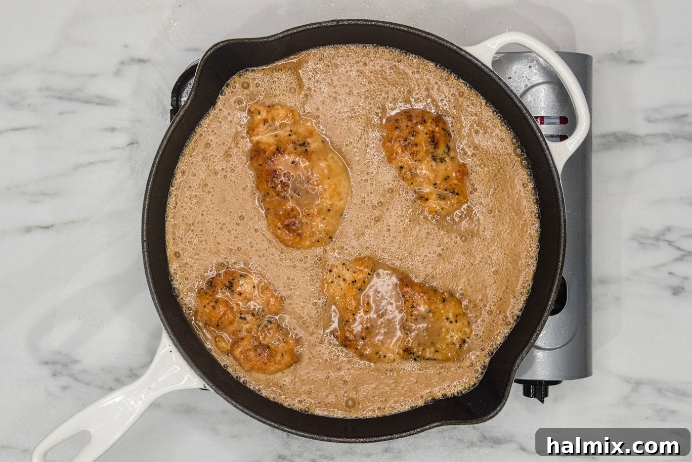 Tropical Coconut Chicken 9 Cooked coconut chicken breasts generously covered in the creamy sauce, simmering gently in a skillet.