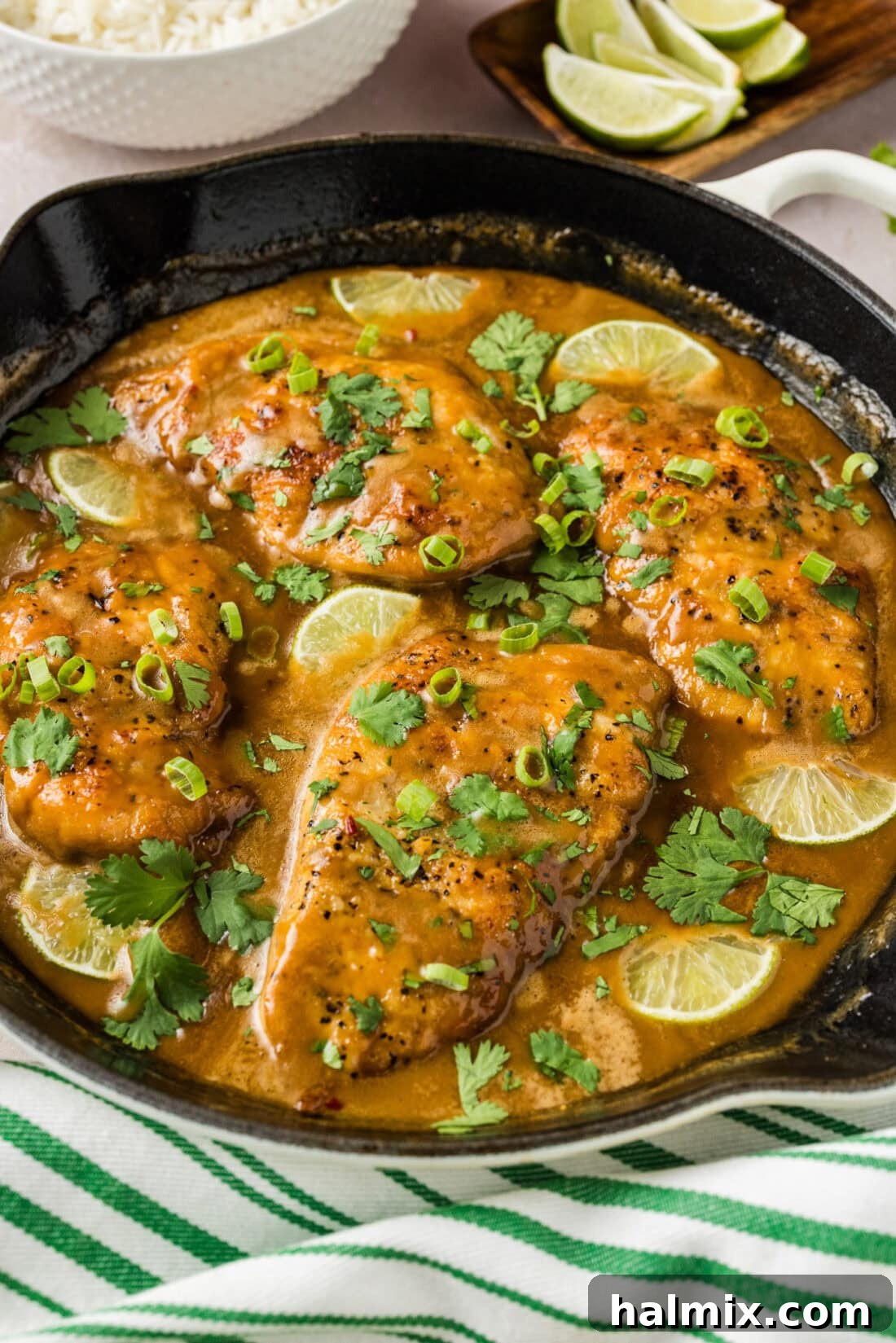 Tropical Coconut Chicken 10 A vibrant bowl of coconut chicken served over fluffy white rice, garnished with fresh lime wedges and green onions.