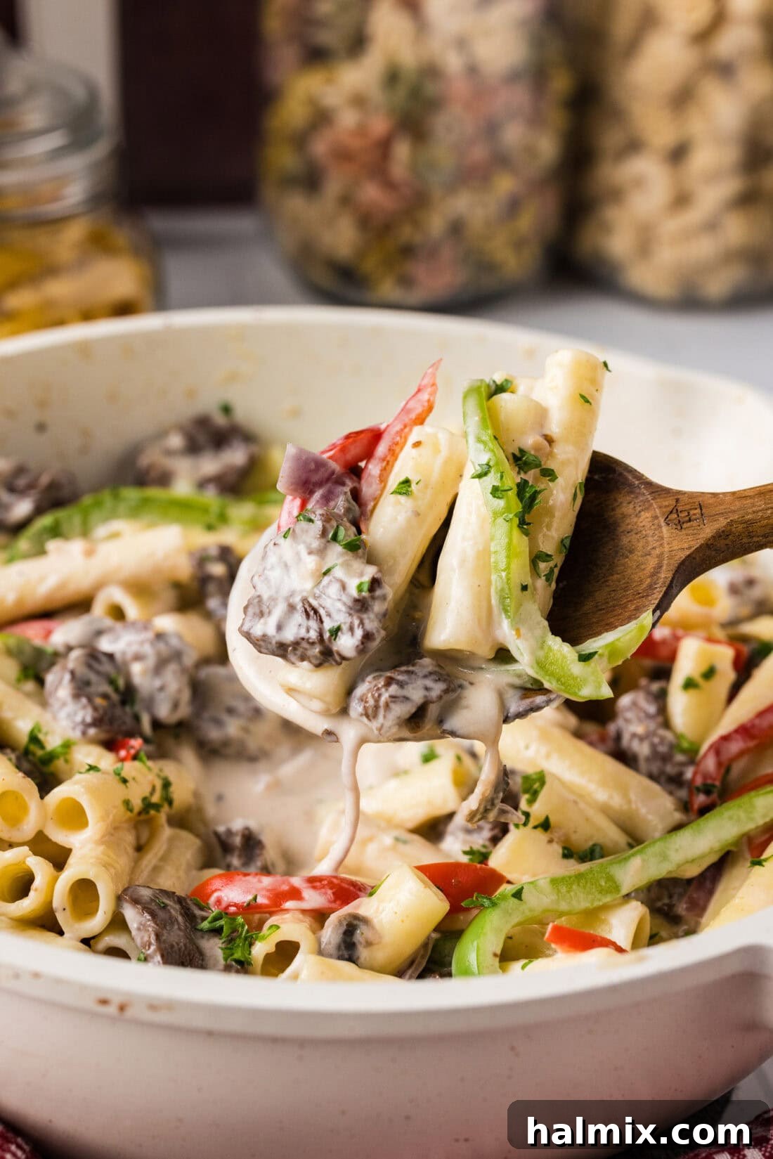 Spoonful of Philly Cheesesteak Pasta held above a skillet of Philly Cheesesteak Pasta