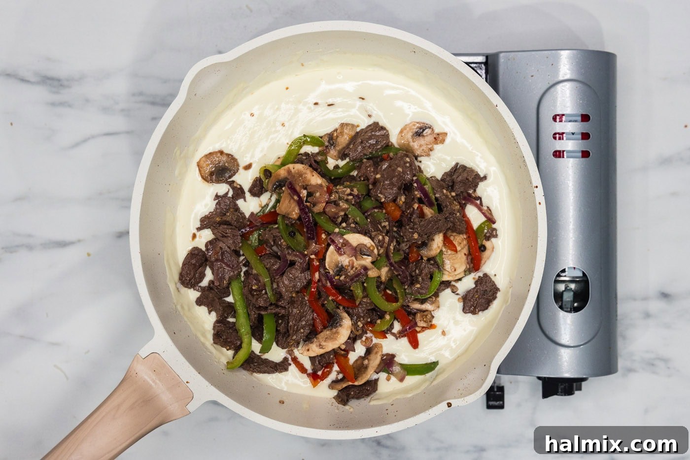 steak and veggie mixture added to skillet of heavy cream and cheese sauce