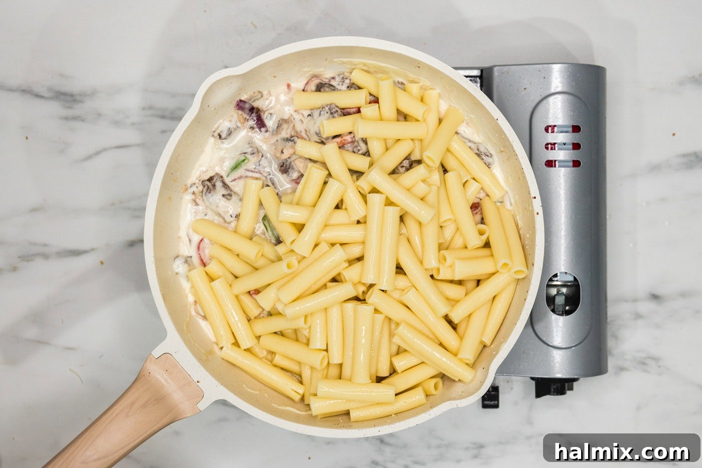 pasta added to skillet with meat, veggies, and cheese sauce