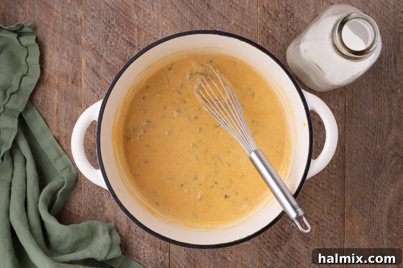 Kicking Cheesy Jalapeño Mac 7 cheese sauce in a pot with a whisk