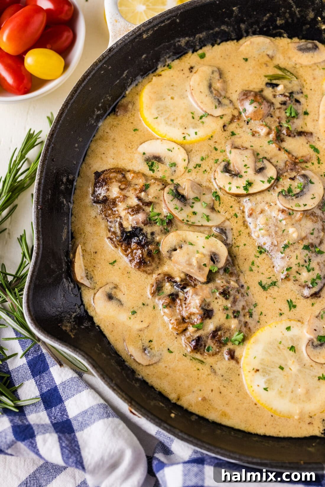 Close up photo of a skillet of Veal Scallopini, with the creamy sauce simmering around the veal cutlets and mushrooms.