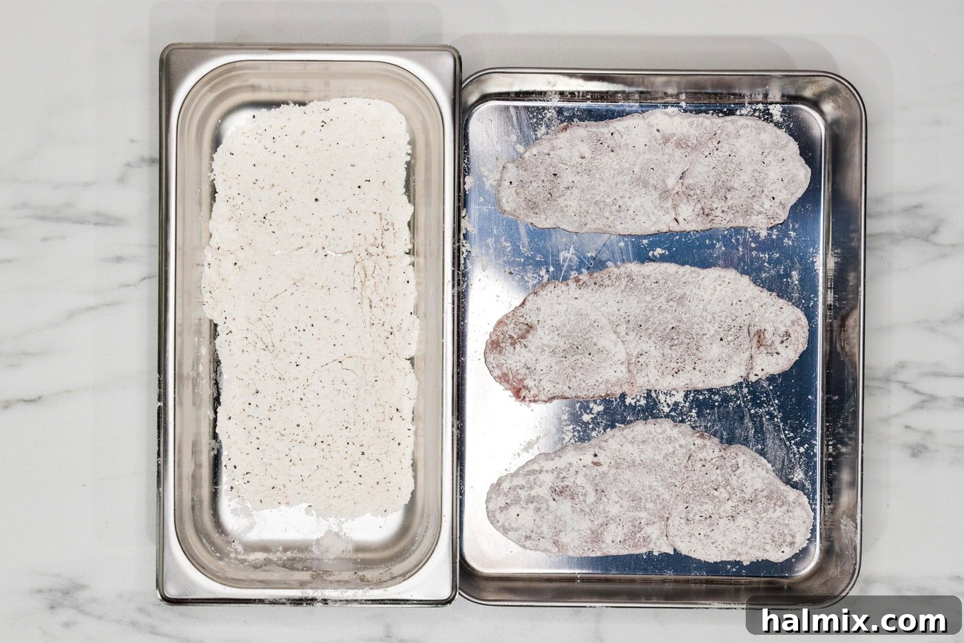 veal cutlets dredged in flour, showing the coating on each piece of meat.