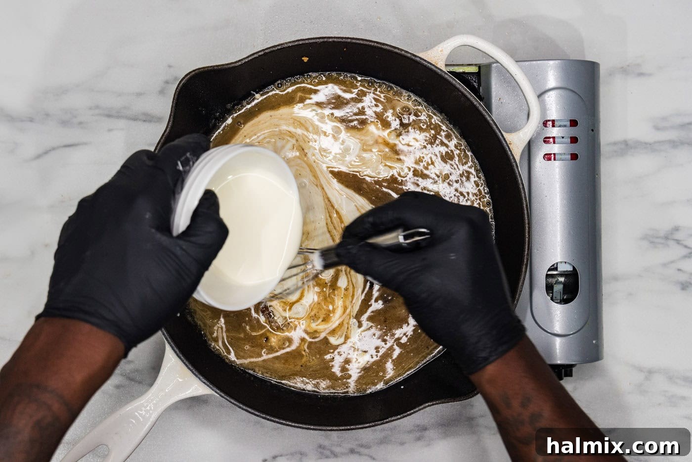whisking heavy whipping cream into skillet with wine, lemon juice, and chicken base, showing the ingredients coming together to form a sauce.