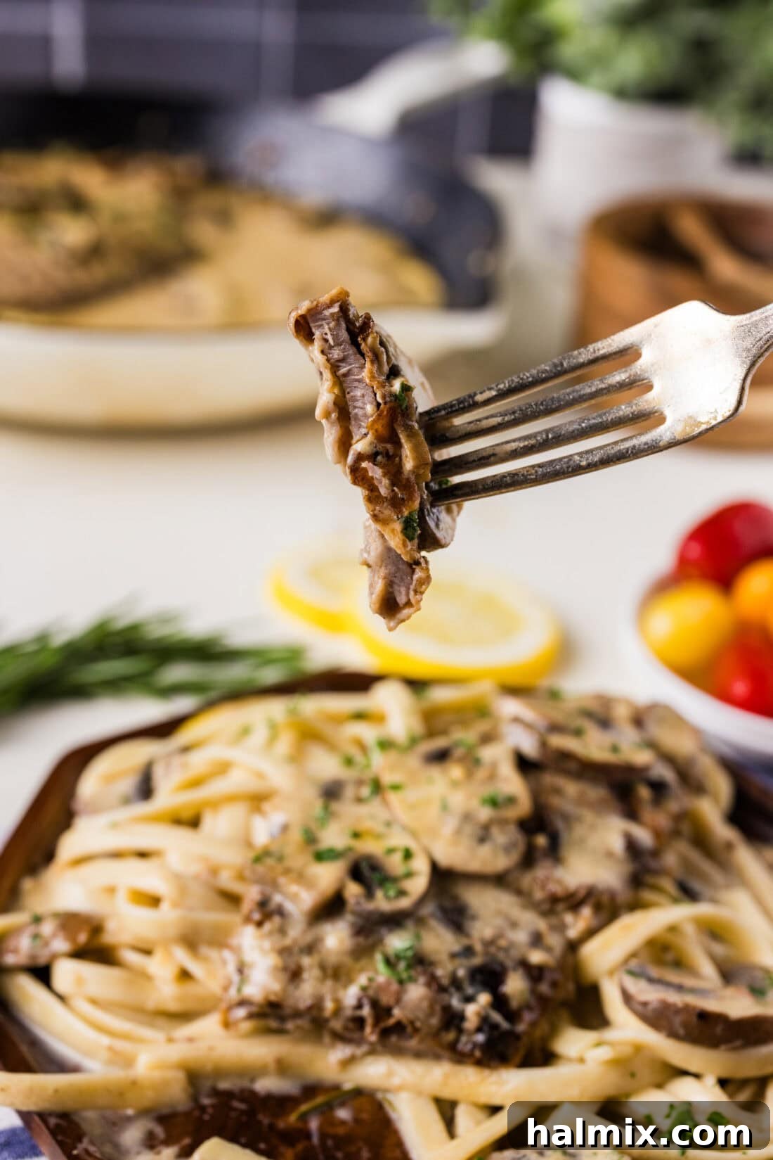 Close up photo of a piece of Veal Scallopini on a fork, highlighting the tender meat and creamy sauce.