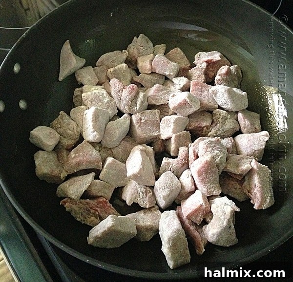 Sautéed beef stew meat browning in a skillet with olive oil