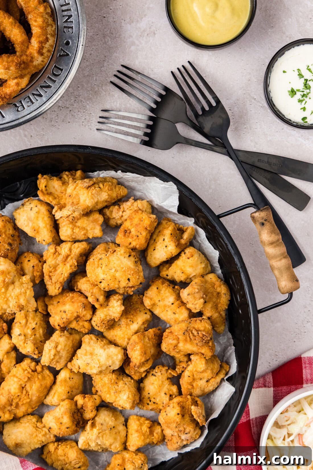 Tray of Popcorn Chicken with forks and dipping sauces on the side