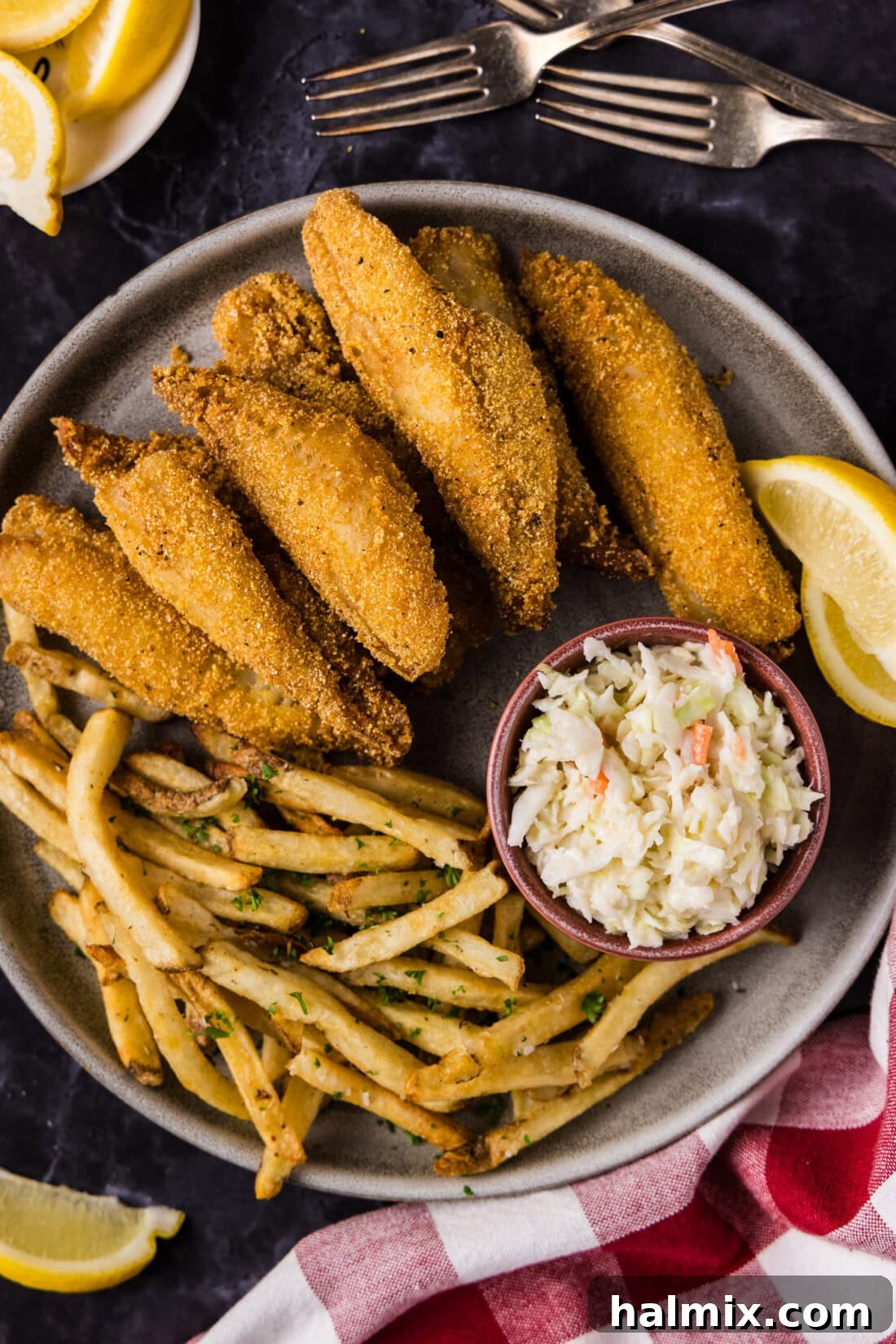 Close up photo of Fried Perch on a plate with fries, coleslaw and lemon wedges on the side