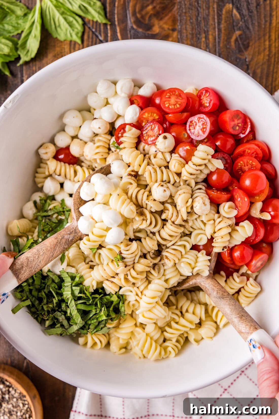 Caprese Pasta Salad being gently mixed in a large serving bowl before serving