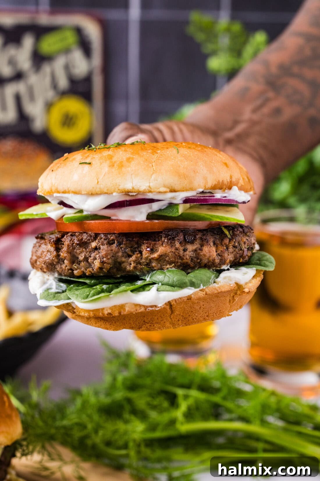 Hand holding a Lamb Burger, showcasing its juicy texture and toppings