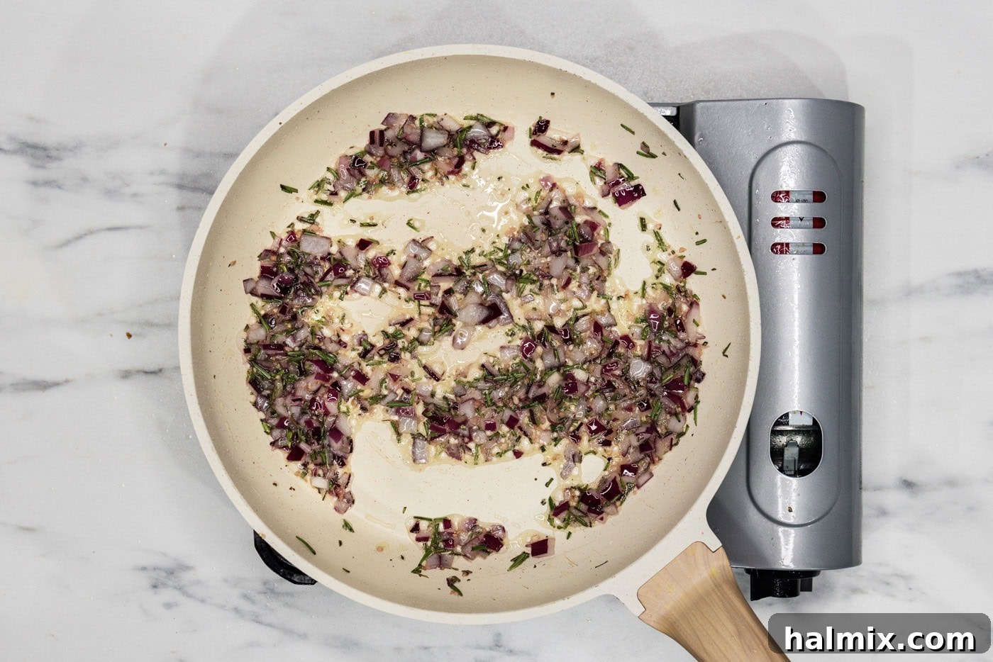 Onion, garlic, and rosemary sautéing in a skillet, filling the kitchen with aroma