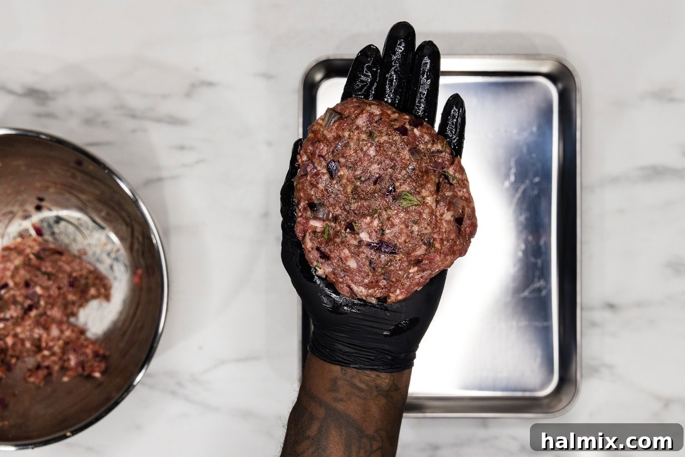 Gloved hand holding a perfectly formed lamb burger patty