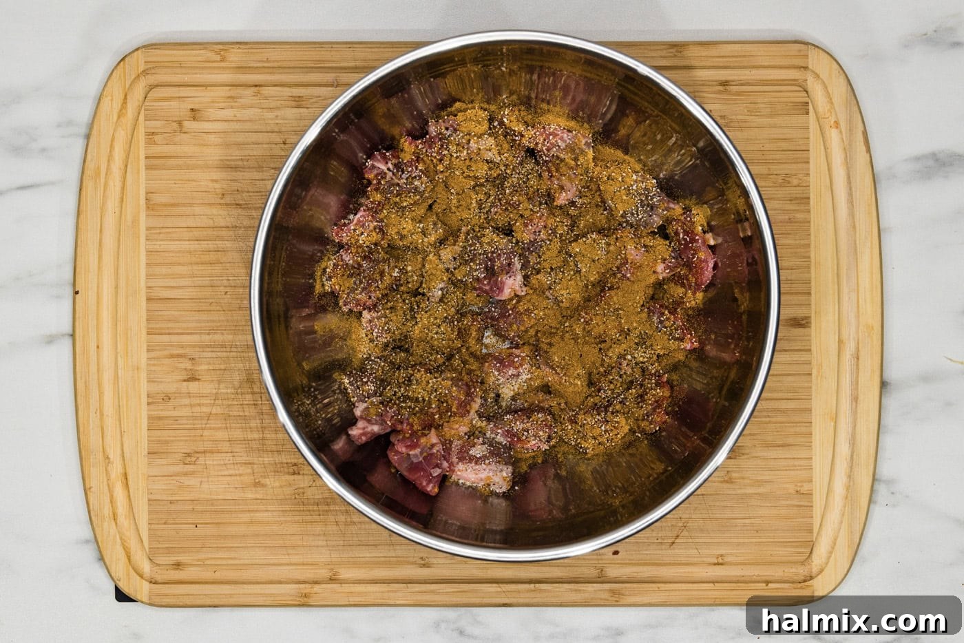 beef cubes in a bowl with seasonings, ready to be cooked