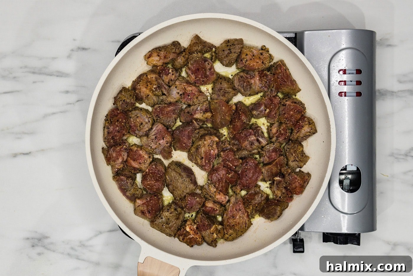 beef cubes searing and browning in a hot skillet