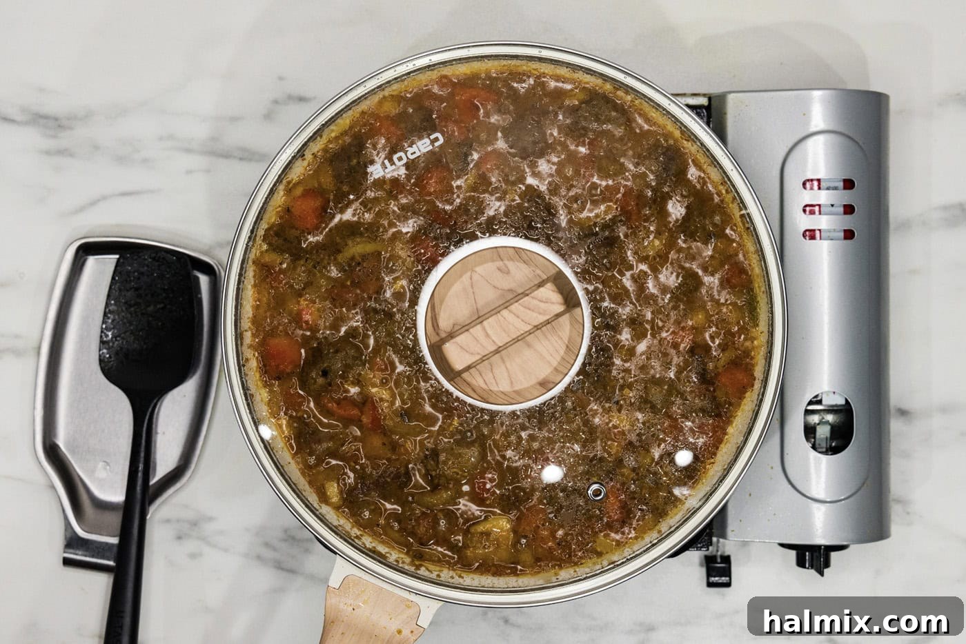 beef curry simmering in a covered skillet on the stovetop