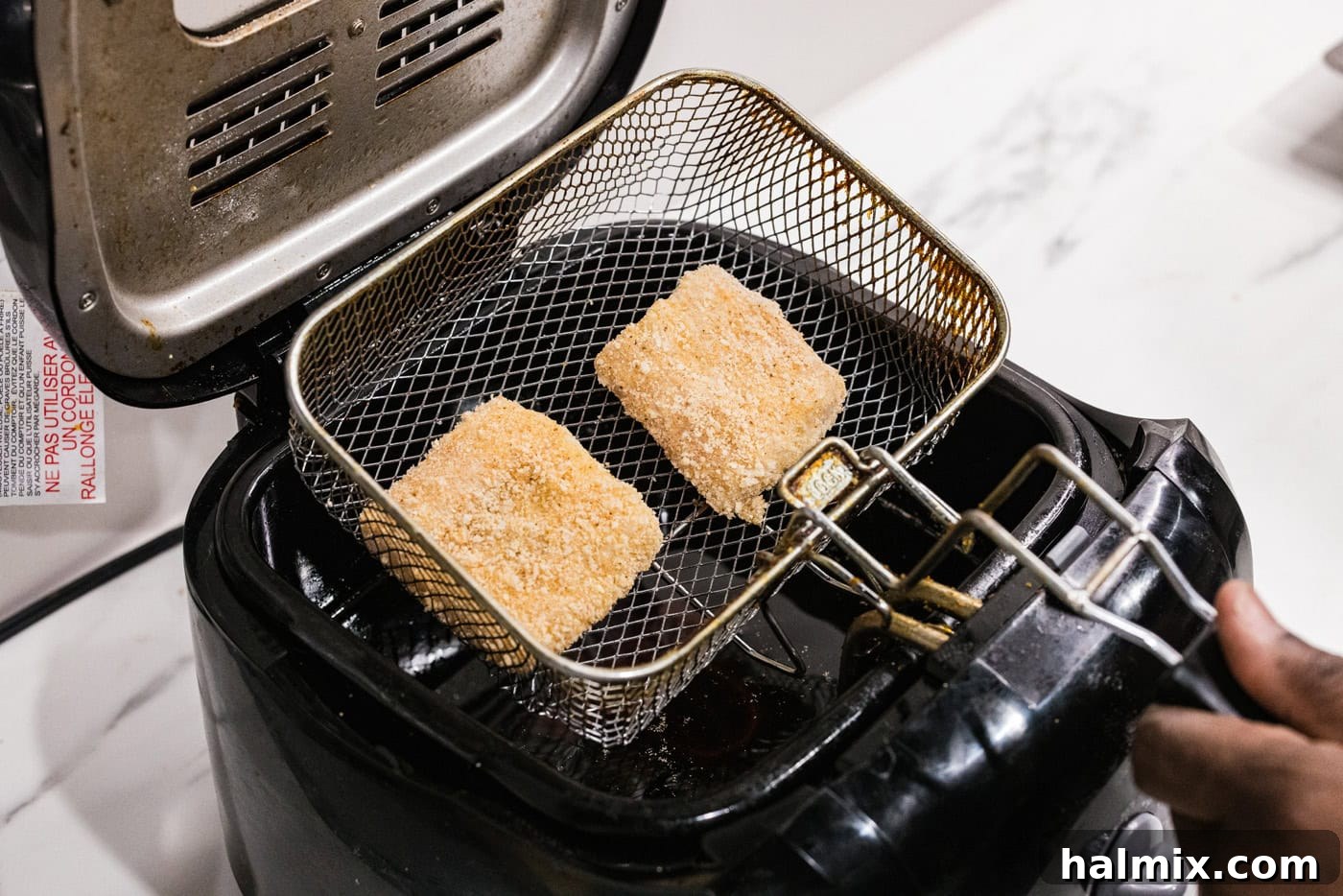 dredged cod patties in a deep fryer basket