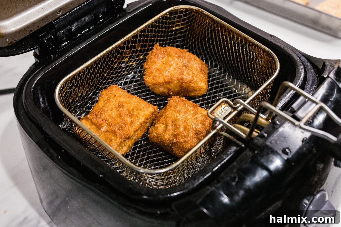 cooked cod patties in a deep fryer basket