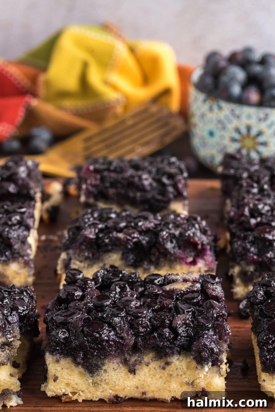 Blueberry Crown Cake 2 A perfectly cut square slice of Easy Blueberry Upside Down Cake resting on a rustic wooden board, showcasing its vibrant blueberry topping and golden-brown edges. The cake looks incredibly moist and inviting, ready to be enjoyed.