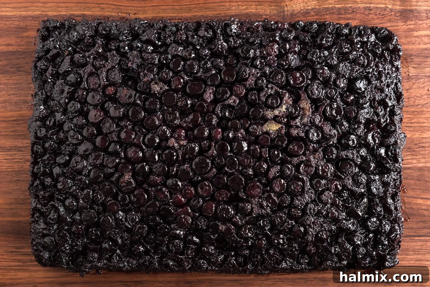 Blueberry Crown Cake 14 The blueberry upside-down cake has been successfully inverted onto a large serving board, revealing the beautiful caramelized blueberry topping glistening on top of the moist cake.