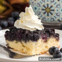 Square of Easy Blueberry Upside Down Cake on a plate topped with whipped cream