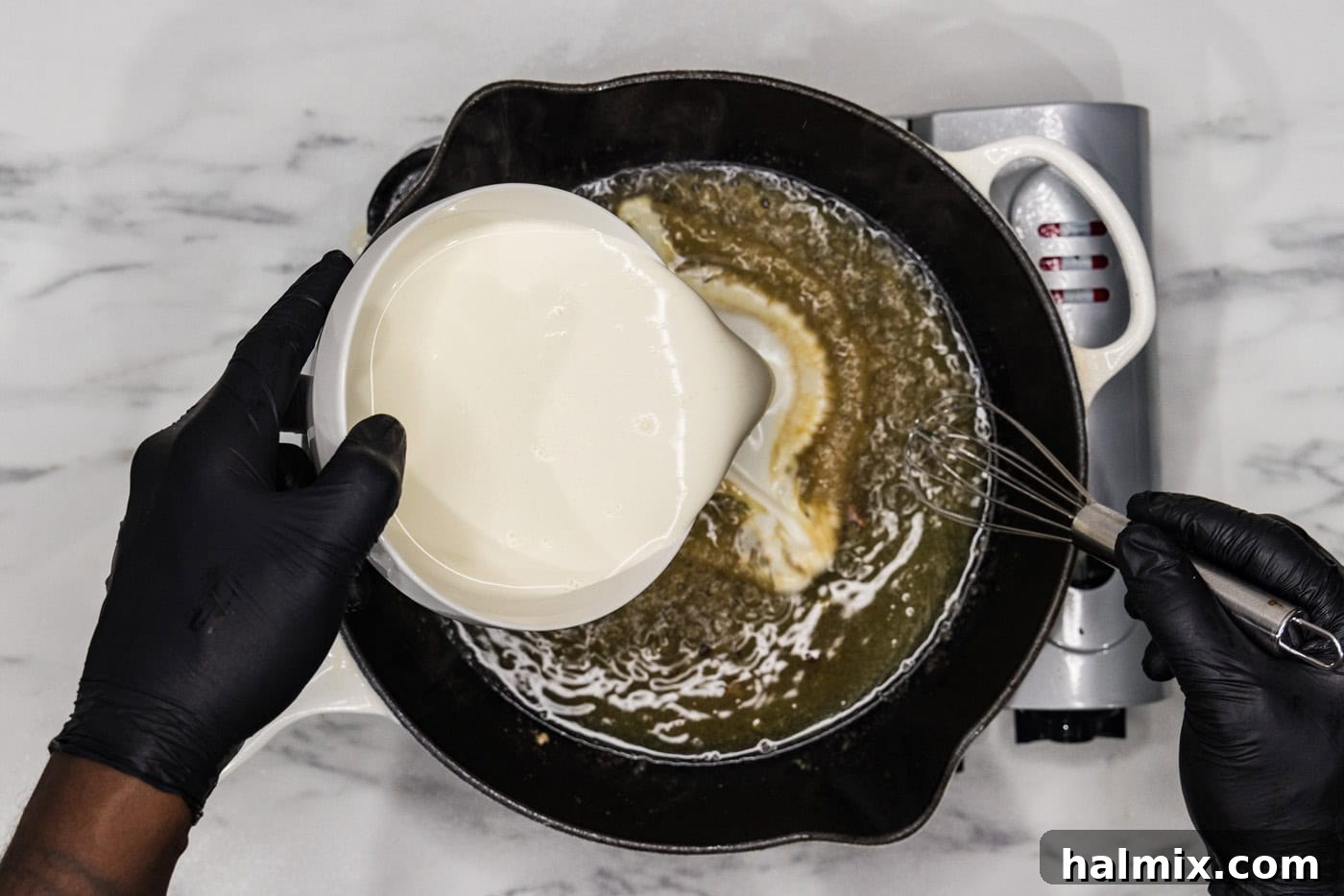 heavy cream being poured into a skillet with broth and wine