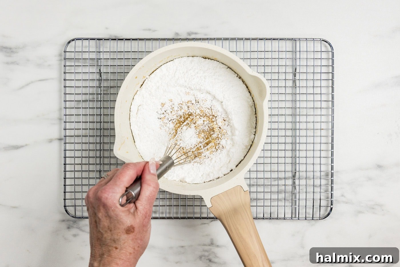 whisking powdered sugar in a saucepan of caramel icing