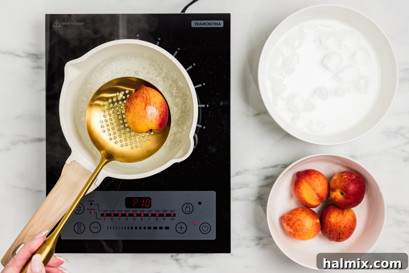 slotted spoon holding peaches over boiling water