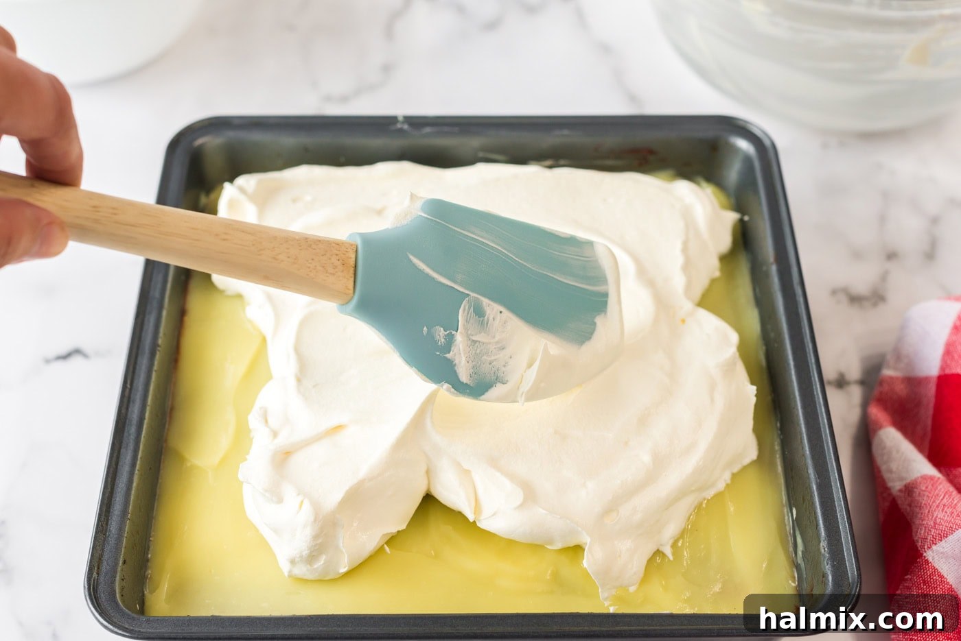Pure Bliss Pan Dessert 12 The final layer of fluffy white Cool Whip being evenly spread across the top of the vanilla pudding.