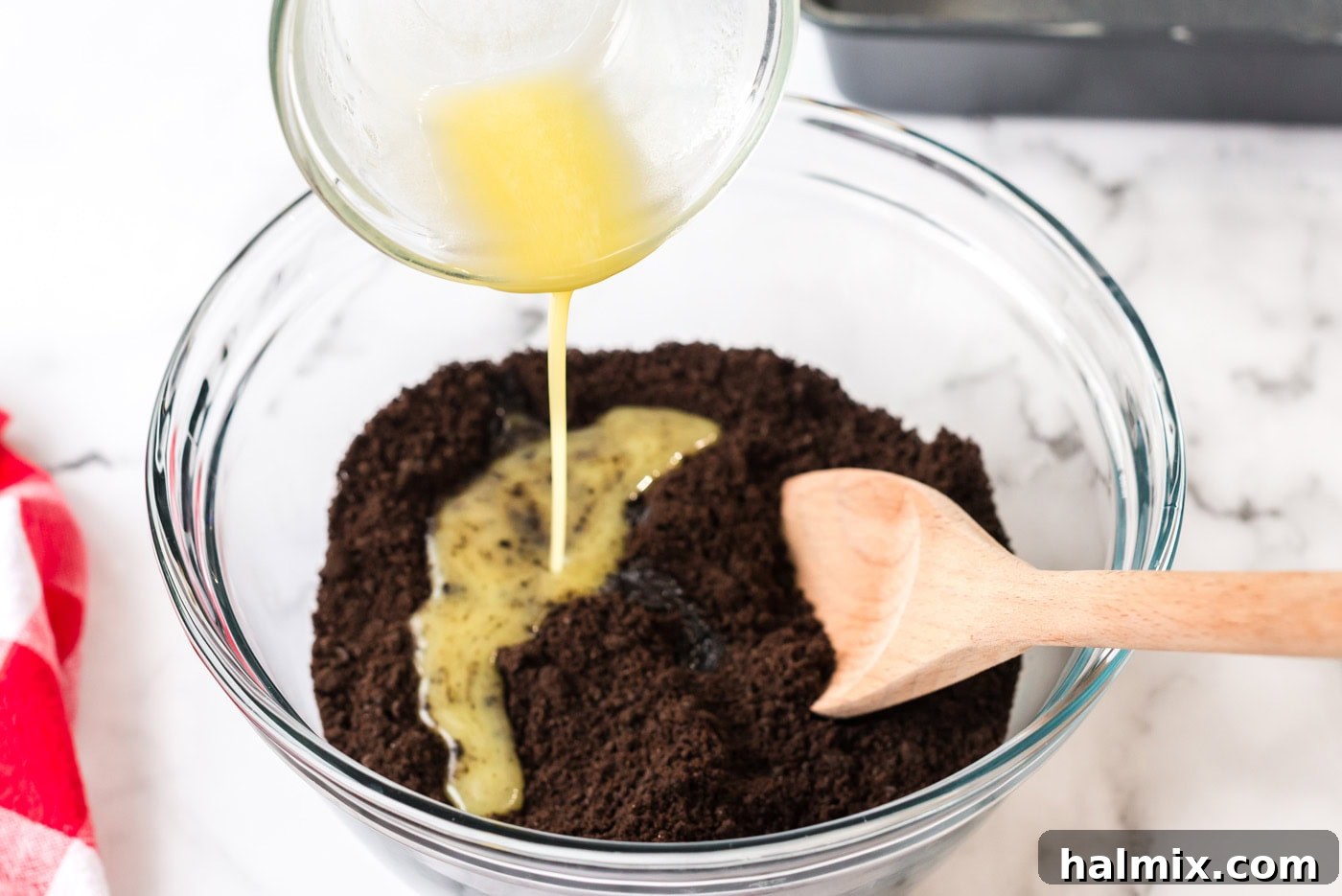 Pure Bliss Pan Dessert 5 Melted butter being poured into finely crushed Oreo crumbs, ready to be mixed for the dessert's base.