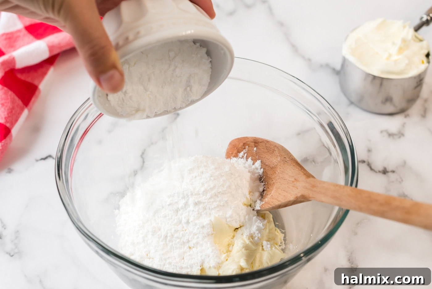 Pure Bliss Pan Dessert 7 Sifted powdered sugar gently falling into a bowl of softened cream cheese, highlighting the preparation of the creamy layer.
