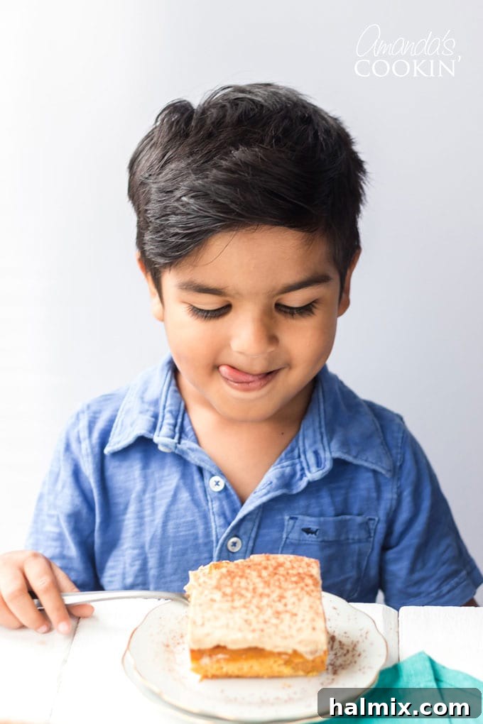 a young boy licking his lips eagerly, waiting to eat a slice of pumpkin magic cake