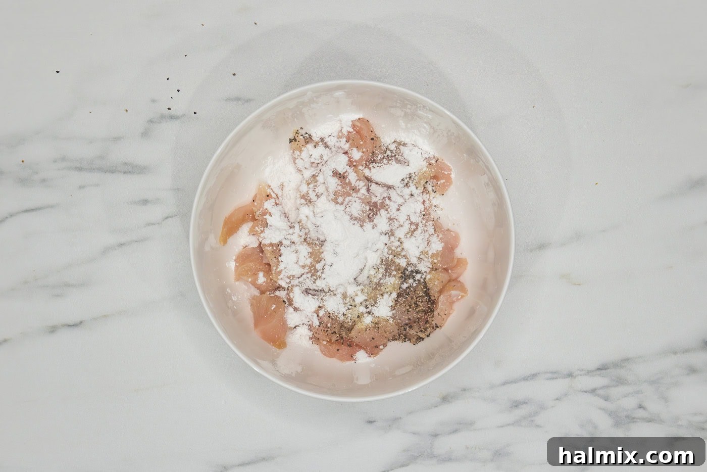 Flavorful Chicken Lo Mein Stir Fry 5 Raw chicken pieces in a bowl, coated with cornstarch and seasonings, ready for stir-frying.