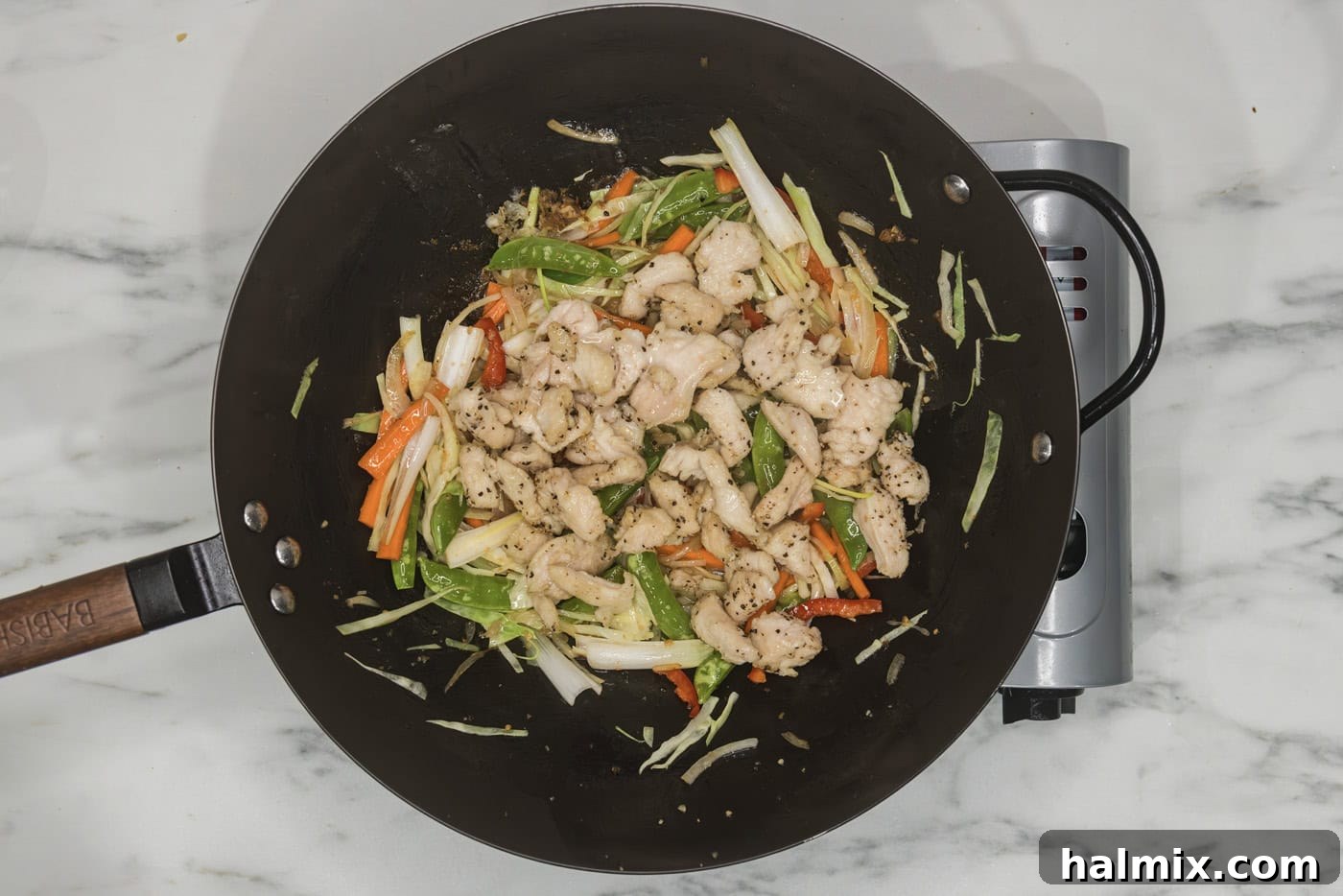 Flavorful Chicken Lo Mein Stir Fry 8 Cooked chicken pieces and sauce being added to the stir-fried vegetables in a wok.