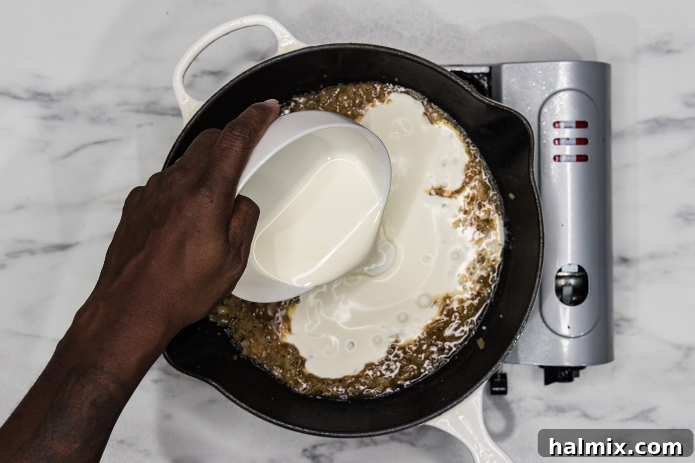 Creamy Sun-Dried Tomato Tuscan Chicken 9 pouring heavy cream into skillet with shallots and garlic