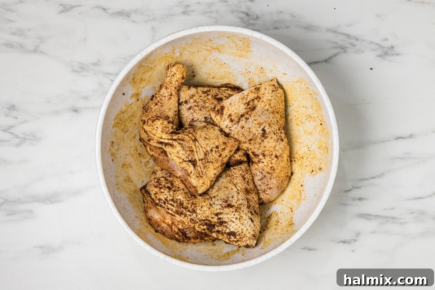 raw chicken quarters in a bowl with wet rub