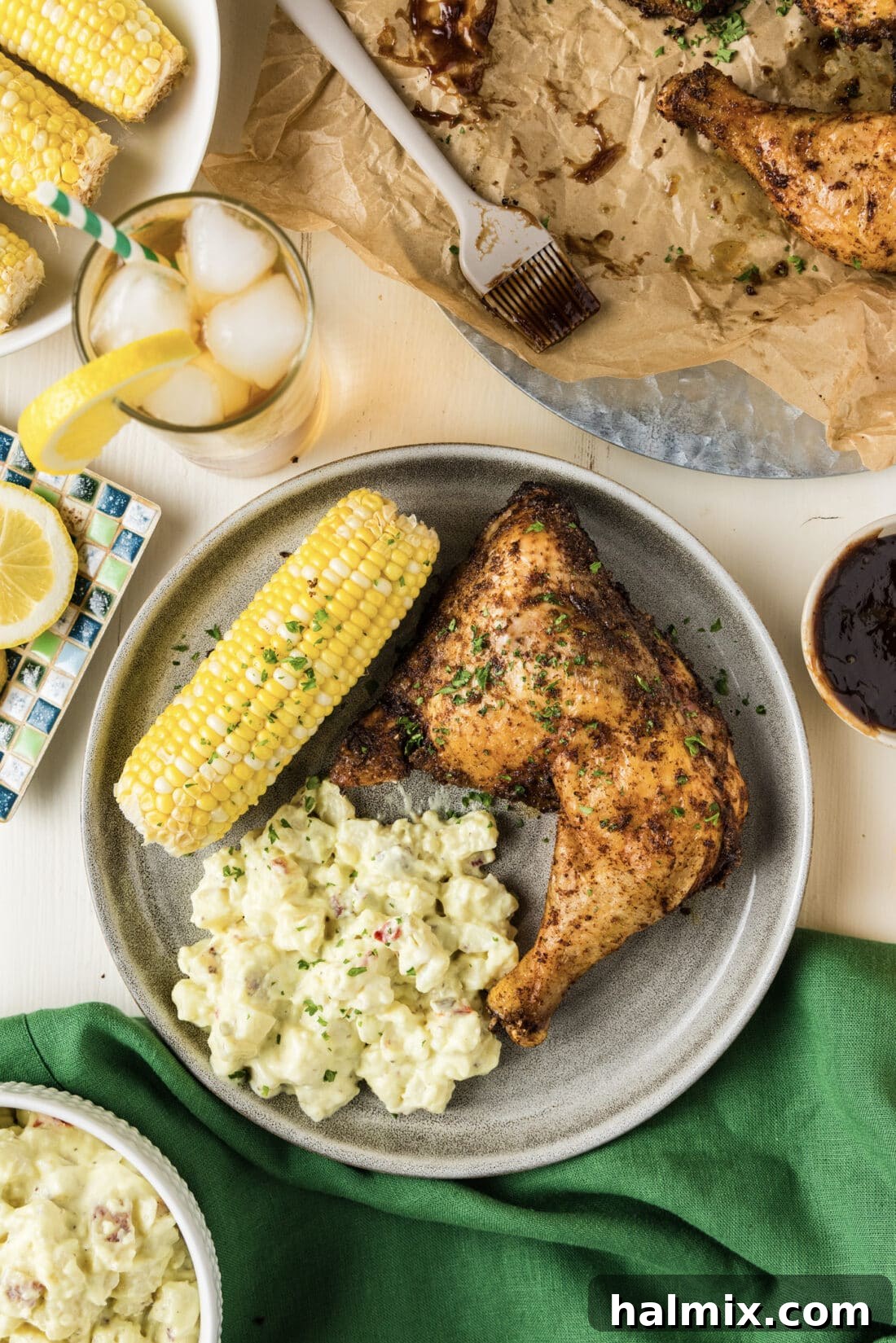 Smoked Chicken Quarter on a plate with potato salad and corn on the cob