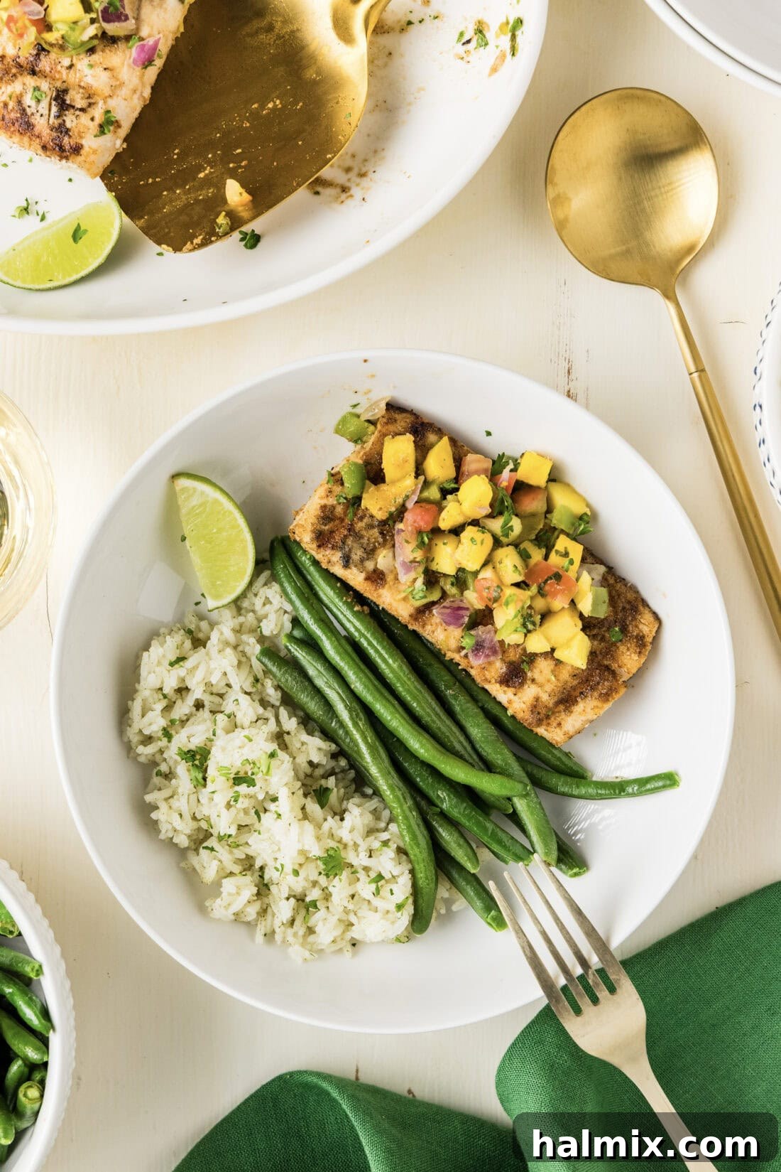 Grilled Mahi Mahi plated with cilantro rice and green beans, garnished with mango salsa