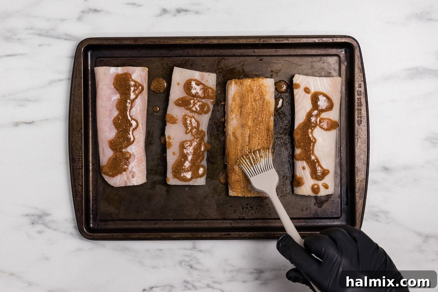 brushing olive oil and seasoning mixture over mahi mahi filets on a pan