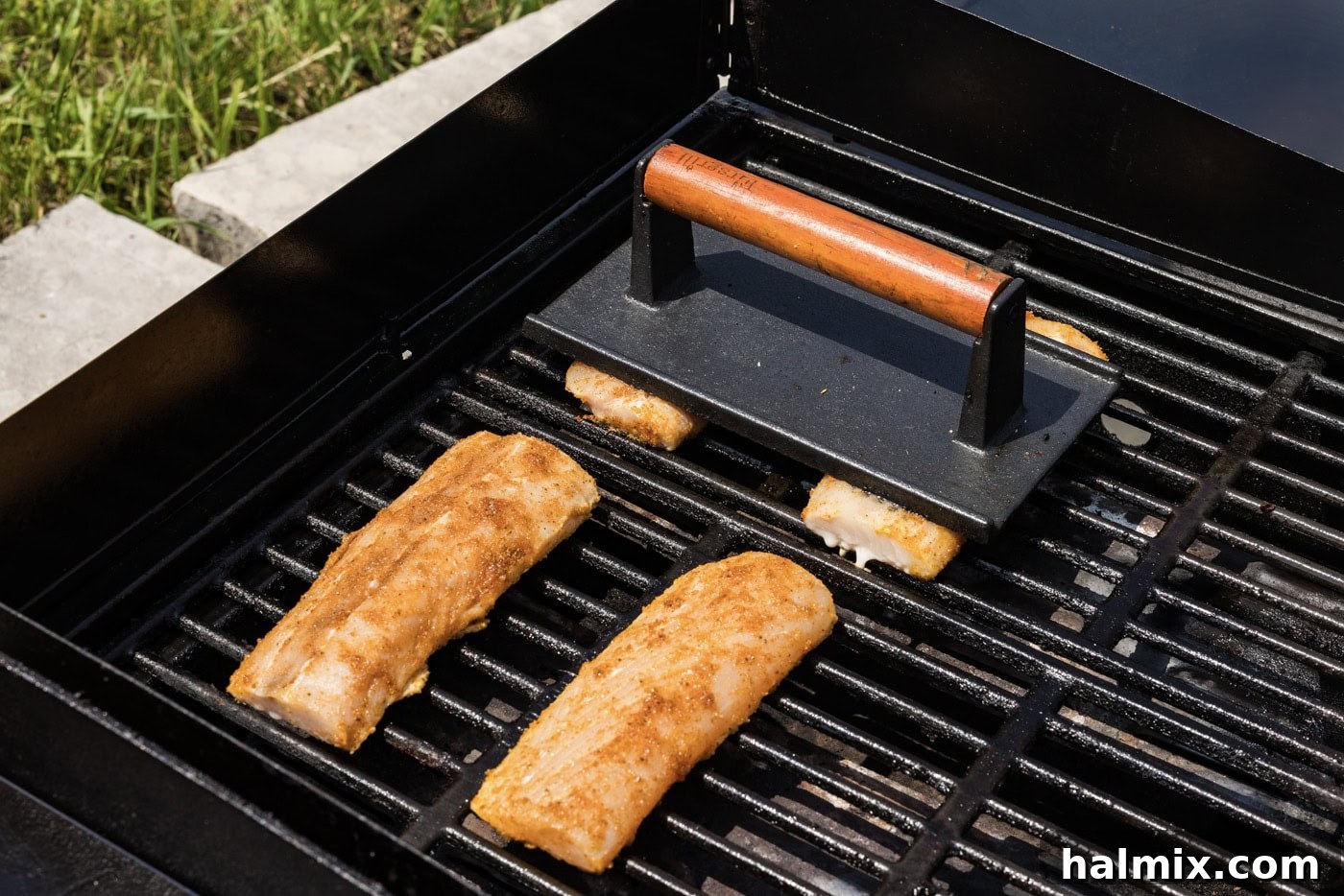 hamburger press over mahi mahi filets on a grill