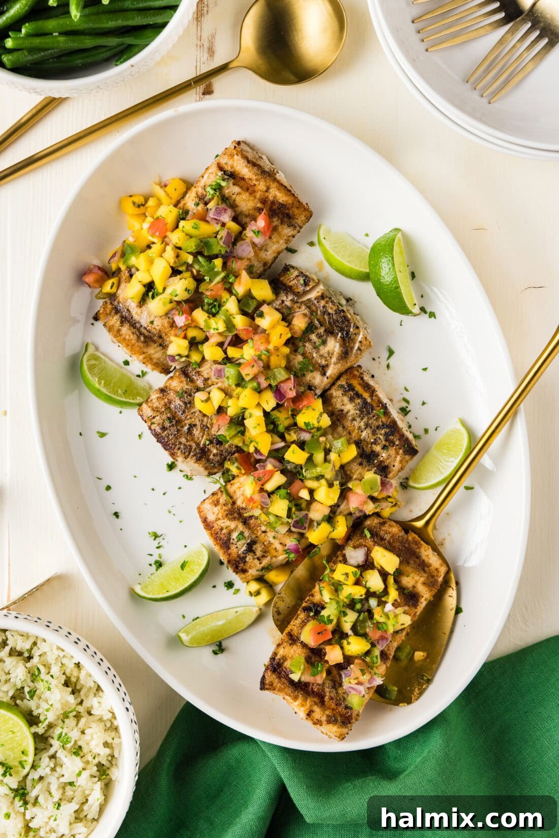 Grilled Mahi Mahi on a white platter with a spatula, garnished with lime